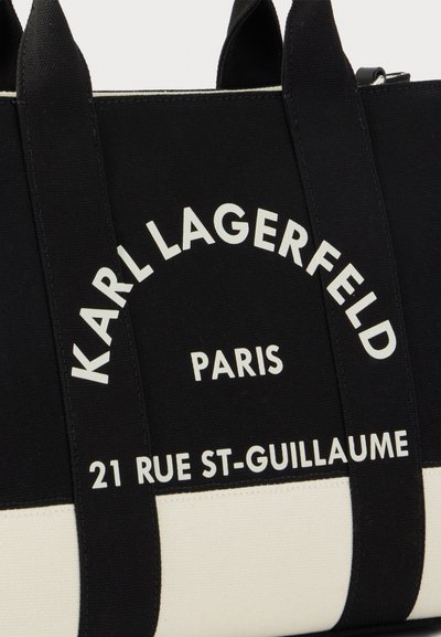 Черна и бяла чанта с черни дръжки с бял надпис: KARL LAGERFELD PARIS 21 RUE ST-GUILLAUME.