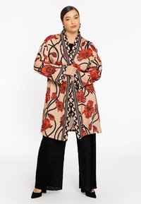 Beige Kimono mit floralem Muster und roten Blumen, schwarzen Akzenten und einem geometrischen Rand. Getragen über schwarzen strukturierten weiten Hosen.