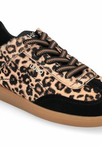 Baskets imprimé léopard avec dessus en fourrure texturée, accents en daim noir, semelle en caoutchouc couleur tan, et lacets noirs contrastants avec oeillets métalliques.