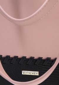 Rosa och svart texturerad handväska med vävd detalj och glänsande Wittchen-logoplack på frampanelen.