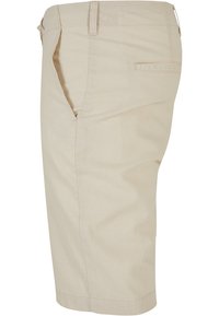 Beige térdihosszú nadrág övhurkokkal, oldalsó zsebbel és hátsó zsebbel, oldalról bemutatva, fehér háttér előtt.