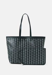 Sac fourre-tout noir et pochette assortie à fermeture éclair avec motif géométrique blanc et fines bretelles sur fond blanc.