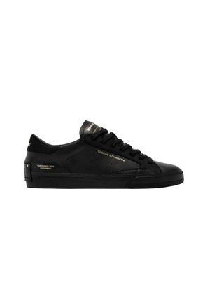 Sneaker nera low-top con lacci davanti, testo oro "Crime London" e piccolo testo laterale "Distressed with no stress" su sfondo bianco.