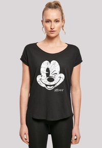 Czarna koszulka z luźnym krojem, z białą grafiką przedstawiającą twarz Micky'ego Mouse'a i podpisem w lewym dolnym rogu. Miękka tkanina, krótkie rękawy.