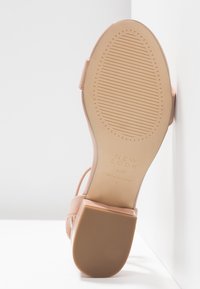 Sandale à talon haut rose avec tige lisse, bride réglable et semelle en caoutchouc à motifs. Caractérisée par un texte embossé sur la semelle.