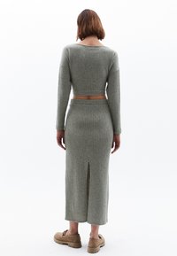 Ensemble deux pièces côtelé vert clair comprenant un haut à manches longues court et une jupe longue avec une fente à l'arrière et une taille élastique.