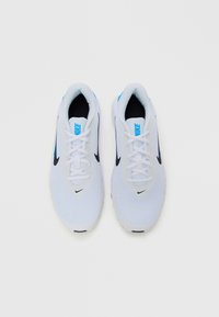 Ein Paar weiße Nike Laufschuhe mit schwarzen Swoosh-Logos und blauen Nike-Branding auf der Zunge, geschnürt und nebeneinander auf weißem Hintergrund platziert.