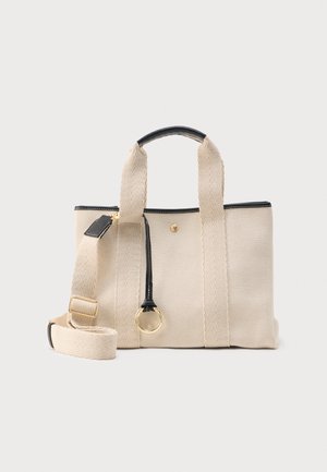 Beige textured mulepose med sort kant, korte håndtag, aftagelig skulderrem og guldringdetalje på lynlåsens trækstykke foran.