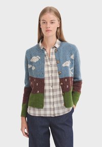 Svetr s modrým tělem a hnědými, zelenými a šedými částmi, se vzory oblaků, dřevěnými knoflíky a žebrovanými manžetami.