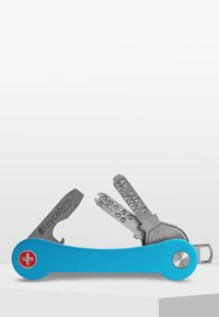 Blå metallnyckelhållare med en schweizisk korslogotyp, har två silvernycklar och en fickklipp för enkel fästning.