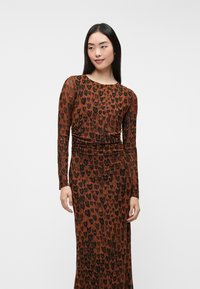 Pika-sleedega pruun kleit musta leopardimustriga. Omab sujuvat siluetti, millel on kogutud detailid vööl. Pehme tekstuur.