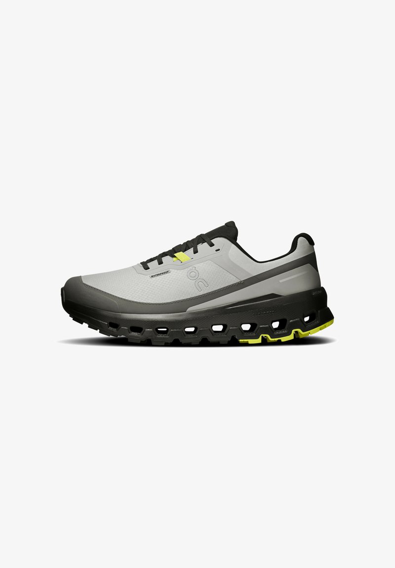 Chaussure imperméable grise avec des accents noirs, dotée d'un dessus texturé, d'une semelle épaisse et rembourrée, et de détails jaunes vifs sur la semelle extérieure.