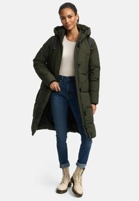 Long, olive-green puffer coat with a hood, featuring a front zipper and side pockets. Worn over a light sweater and denim jeans, with beige boots.