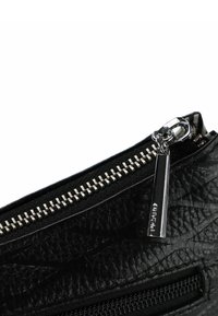 Bolso de cuero negro con acabado texturizado, que presenta una cremallera y un tirador plateados. La costura expuesta a lo largo del borde añade detalle.