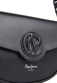 La borsa a spalla in pelle nera presenta una finitura testurizzata, un logo impresso e dettagli in argento. Il design è compatto con chiusura a patta.