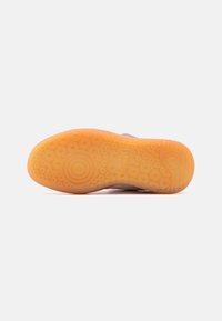 Gummisål med cirkulære mønstre, orange i farven. Glat tekstur med riller for godt greb og et logo-detalje på hælområdet.