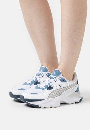Witte sportschoenen met lichtblauwe en grijze accenten, meshpanelen, een getextureerde zool en veters. Heeft een zichtbaar logo op de tong.