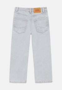 Ανοιχτό γκρι τζιν παντελόνι με ίσια γραμμή και δύο πίσω τσέπες, διακοσμημένο με δερμάτινο ταμπελάκι καφέ χρώματος με την επιγραφή "JACK & JONES".