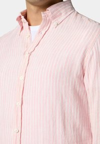 Camicia a righe rosa chiaro realizzata in tessuto di lino; presenta un colletto button-down, bottoni bianchi e una vestibilità casual.
