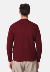 Maglione bordeaux lavorato a maglia con una texture a coste, maniche lunghe e scollo rotondo, caratterizzato da un'orlo dritto e una vestibilità morbida.
