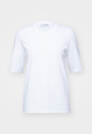 Weißes Baumwoll-T-Shirt mit kurzen Ärmeln, rundem Ausschnitt und einem dezenten gestickten Logo auf der Brust. Glatte Textur, klassischer Schnitt.