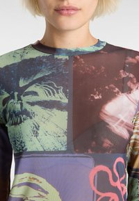 Long-sleeve top featuring a multicolored print with graphic patterns in shades of blue, green, red, and brown on a smooth texture.