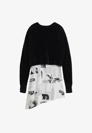 Fekete bolyhos crop pulóver, amelyet egy fehér ruhával kombinálnak, fekete és szürke újságmintával, aszimmetrikus szegéllyel.
