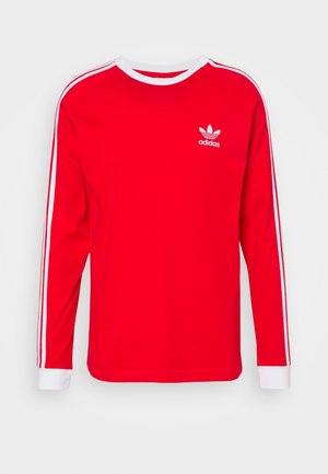 Rotes Langarmhemd aus weichem Stoff, mit weißen Streifen an den Schultern und Ärmeln, sowie einem kleinen weißen Adidas-Logo auf der Brust.