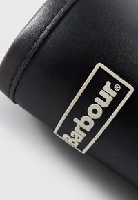 Zwarte leren portemonnee met een gladde textuur, voorzien van een zilveren rechthoekig logo met de tekst "Barbour" duidelijk zichtbaar.