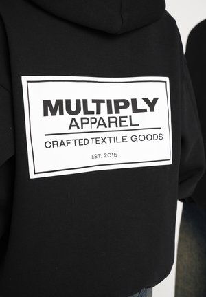 Black hoodie featuring a large white graphic label on the back that reads "MULTIPLY APPAREL CRAFTED TEXTILE GOODS EST. 2015."