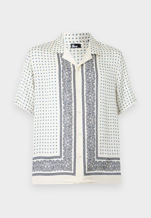 Rövid ujjú, krémszínű, gombos ing sötétkék paisley mintákkal és kis kereszt alakú díszítésekkel, széles gallérral és laza szabással.