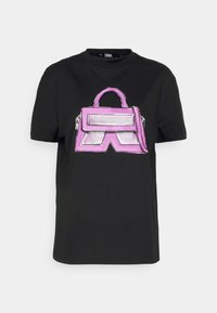 Camiseta negra de manga corta con un gran gráfico de bolso morado y el texto "Karl Lagerfeld" en el centro frontal.