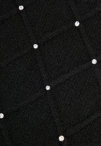 Tessuto nero lavorato a maglia con un motivo a rombi testurizzato, arricchito da piccoli strass trasparenti distribuiti uniformemente.