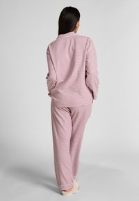 Σετ πιτζάμες σε ροζ και λευκό καρό σχέδιο, κατασκευασμένο από απαλό ύφασμα· περιλαμβάνει πουκάμισο με κουμπιά και ταιριαστό παντελόνι, με μακριά μανίκια και άνετη εφαρμογή.