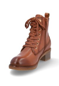 Botín de cuero marrón con cordones gruesos, cremallera lateral, lengüeta, tacón de madera apilada y suela de goma.