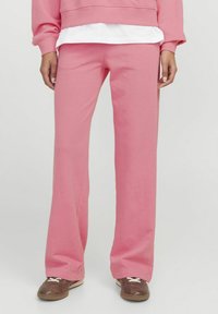 Roza flare hlače iz mehke mešanice bombaža. Imajo srednji pas in sproščen kroj, v kombinaciji s rjavimi športnimi čevlji.