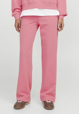 Pantaloni da tuta rosa a campana realizzati in morbido tessuto misto cotone. Presentano una vita media e una vestibilità rilassata, abbinati a sneakers marroni.