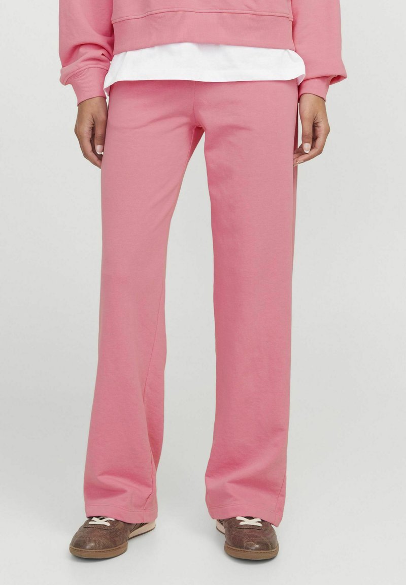 Roza flare hlače iz mehke mešanice bombaža. Imajo srednji pas in sproščen kroj, v kombinaciji s rjavimi športnimi čevlji.