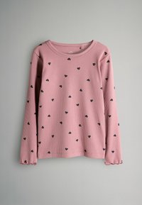 Långärmad rosa ribbad skjorta med svarta spridda hjärtan och rynkade manschetter som hänger mot en grå bakgrund.