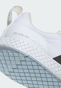 Valkoinen sneaker, jossa on teksturoitu kangasulkko, mustat yksityiskohdat ja kuminen pohja, jossa on ruudullinen kuvio. "ZERO DEGREE DROP" -merkintä sivulla.