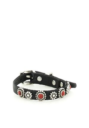 Bracciale in pelle nera con borchie argentate a forma di fiore e accenti in pietra rossa rotonda, fissato da una fibbia argentata.