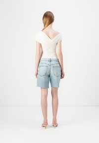 Vit off-shoulder topp med draperad tyg; parat med ljusblå denimshorts med fransade kanter och bakfickor. Enkelt, minimalistiskt mönster.