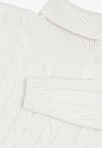 Maglione bianco lavorato a maglia con un alto colletto a coste e motivo a trecce. La texture è morbida, con polsini a coste a contrasto.
