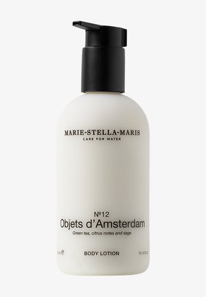 Bouteille de lotion corporelle cylindrique blanche avec un bouchon-pompe noir ; présente un texte noir décrivant la marque et le parfum. Capacité de 300 ml.