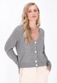 Grijze gebreide cardigan met V-hals, voorzien van een gestructureerd kabelpatroon en vijf witte knopen aan de voorkant. Ribgebreide zoom en mouwmanchetten.