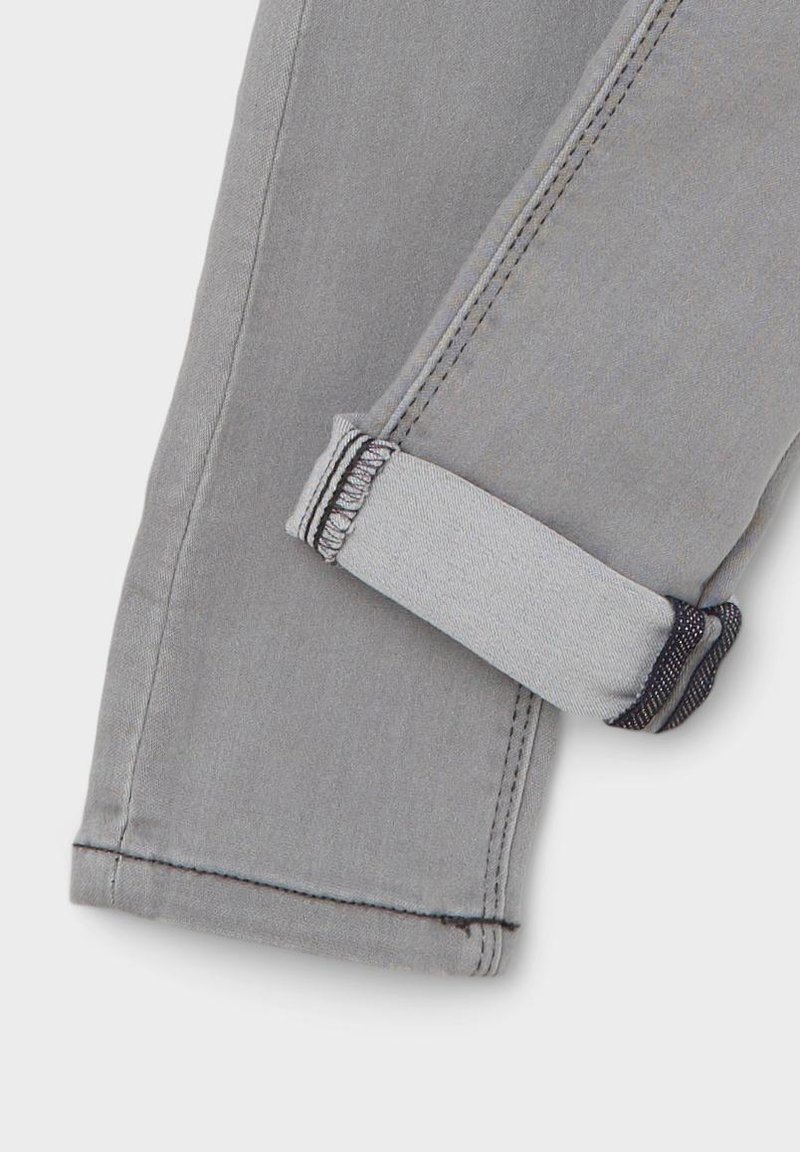 Grauer Denim-Stoff mit umgeschlagenem Saum, kontrastierenden Nähten und einer glatten Textur. Verfügt über einen sicheren Riegel mit schwarzem Faden.