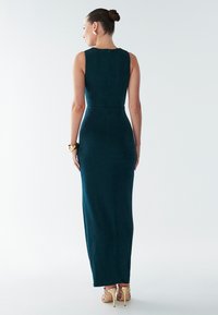 Turquoise, mouwloze avondjurk met een aansluitend ontwerp, een knielange split aan de achterkant en een gladde textuur. Afgewerkt met subtiele naden en een rits aan de achterkant.