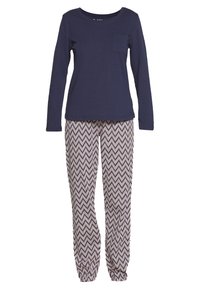Haut à manches longues bleu marine avec une poche sur la poitrine, associé à un pantalon de pyjama élastique crème et noir à motif chevrons.