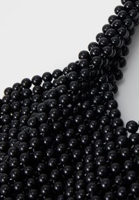 Black bead necklace composed of uniform, glossy spherical beads, interconnected, featuring a smooth texture and an even shine throughout.