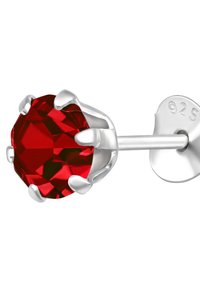 Orecchino a stud in cristallo rosso, forma rotonda, con una montatura in metallo argentato 925 caratterizzata da quattro artigli simili a punte. Riflesso della luce sulle faccette.